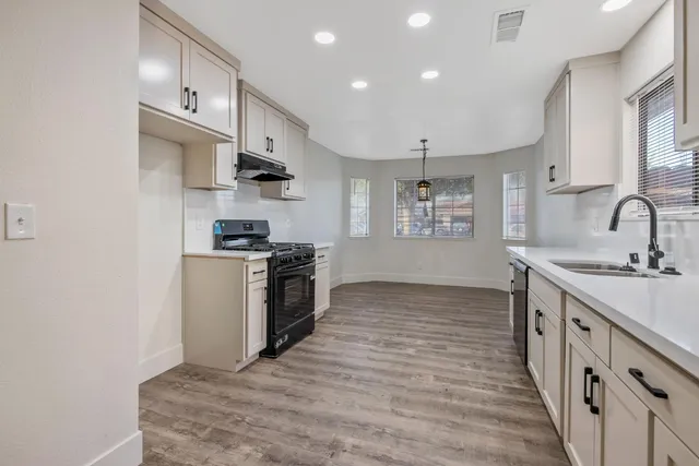 a kitchen with stainless steel appliances a sink stove and cabinets