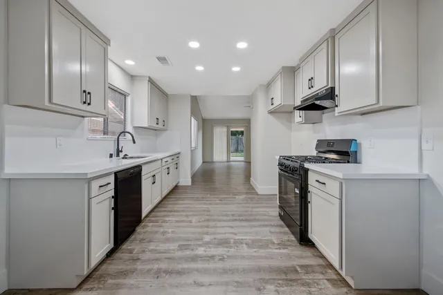 a large kitchen with stainless steel appliances granite countertop a lot of counter space and wooden floor