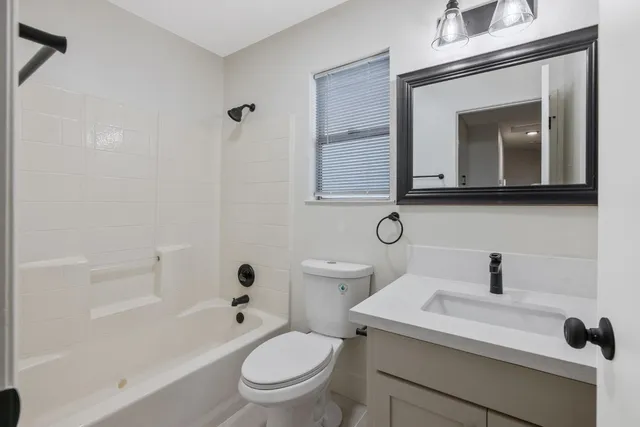 a bathroom with a toilet a sink a mirror and vanity