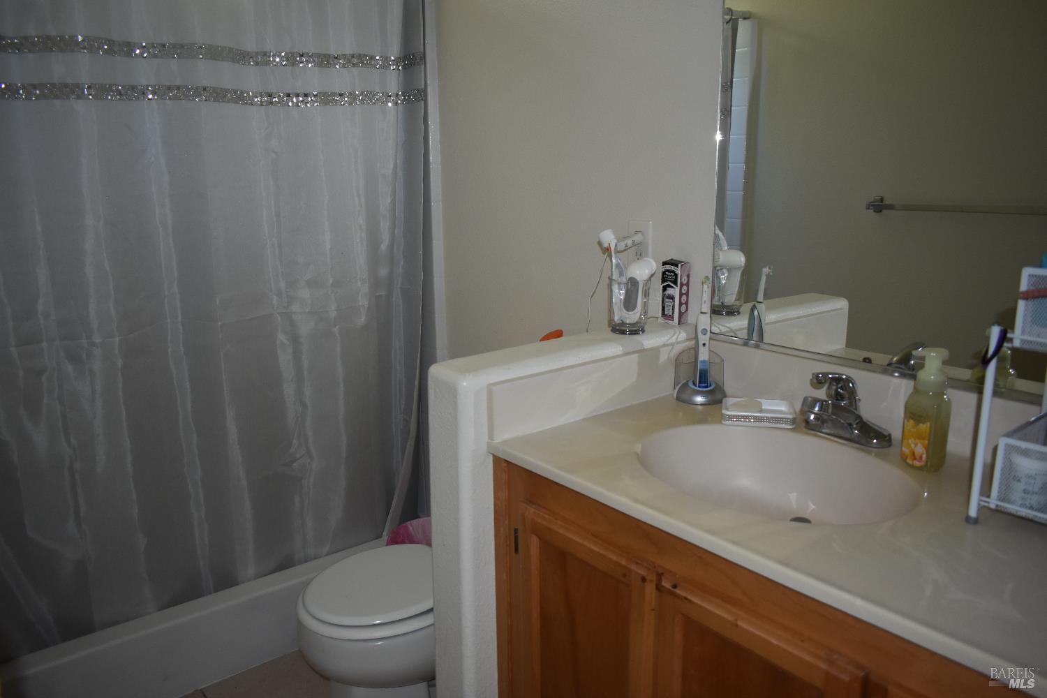 2507 Winterhaven Avenue Santa Rosa, CA 95404 - Photo 12 of 27 a bathroom with a sink a toilet a mirror and shower curtain