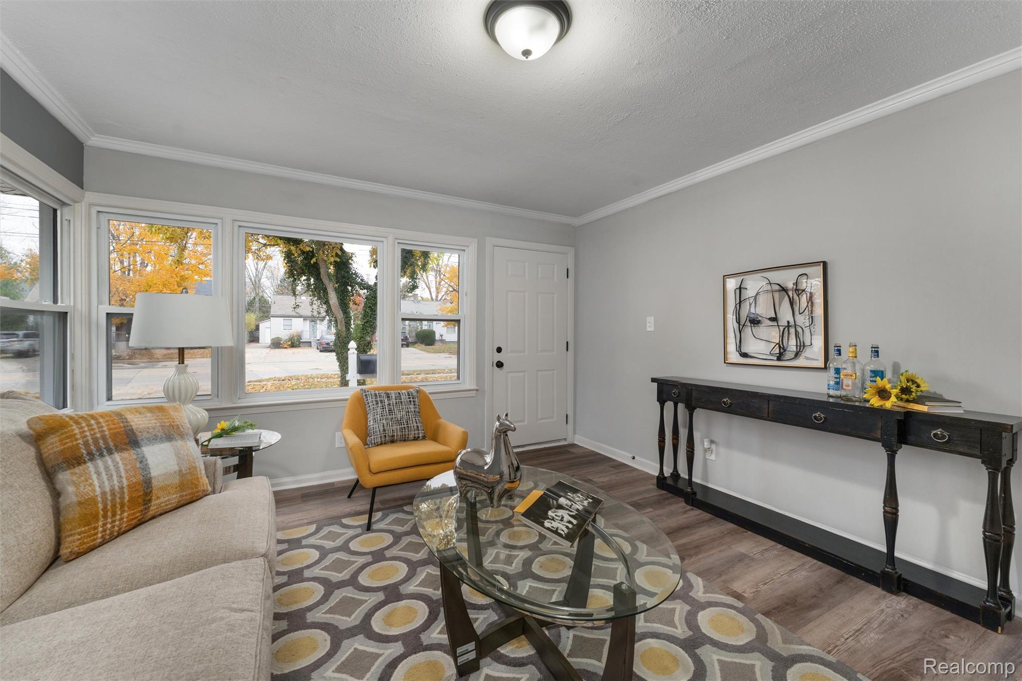 Wood-finish flooring, white trim, light gray painted walls, multiple windows, white entry door