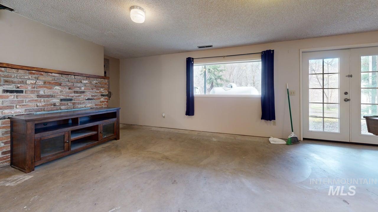 196 Main Street Juliaetta, ID 83535 - Photo 16 of 27 Unfurnished living room featuring french doors, concrete floors, and a textured ceiling