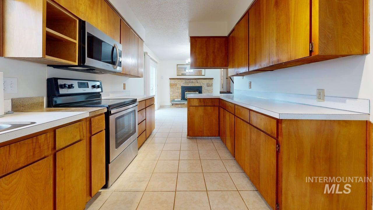 196 Main Street Juliaetta, ID 83535 - Photo 3 of 27 Kitchen with wood finish cabinets, stainless steel appliances, light countertops, a peninsula, and light tile patterned floors