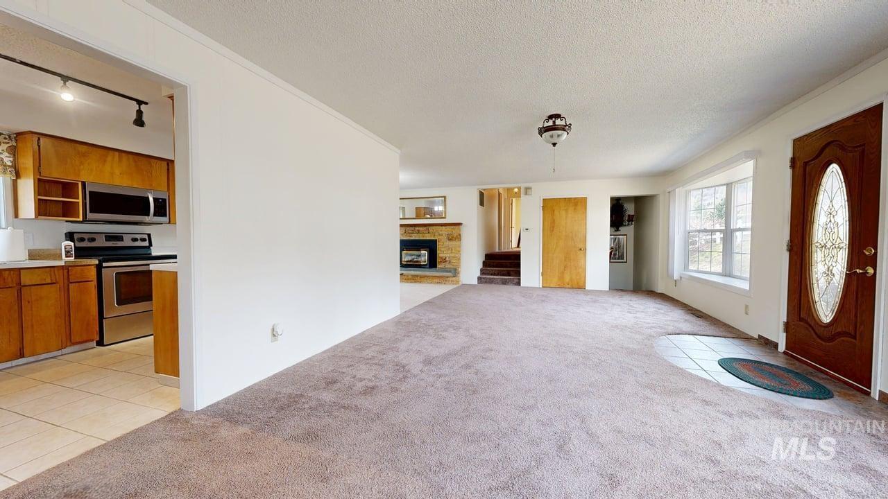 196 Main Street Juliaetta, ID 83535 - Photo 5 of 27 Foyer entrance with rail lighting, light carpet, a fireplace, a textured ceiling, and ornamental molding