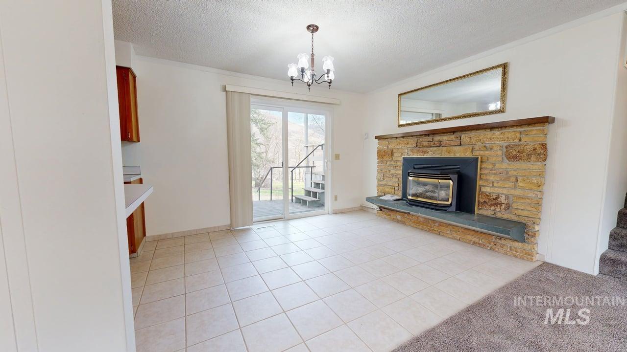 196 Main Street Juliaetta, ID 83535 - Photo 9 of 27 Unfurnished living room with light tile patterned floors, a textured ceiling, hanging lights, and a fireplace