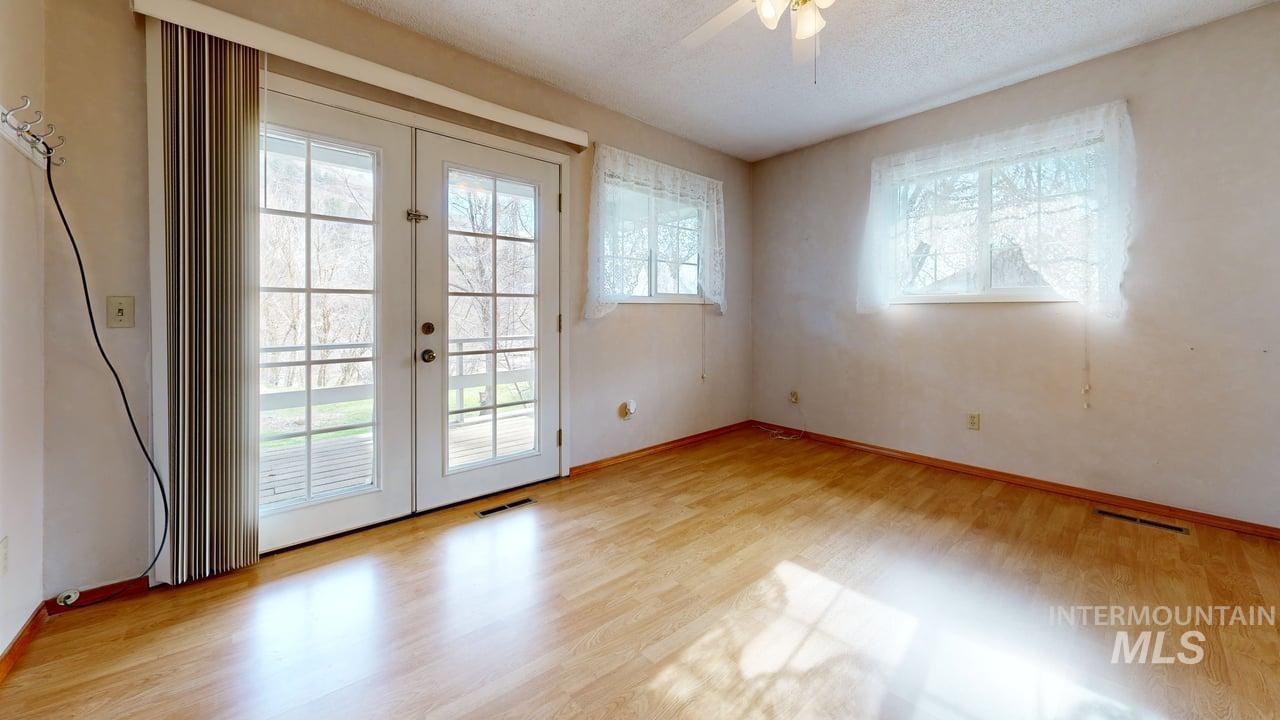 196 Main Street Juliaetta, ID 83535 - Photo 10 of 27 Doorway with french doors, wood finished floors, ceiling fan, and a textured ceiling