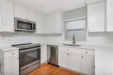 a kitchen with white cabinets stainless steel appliances and sink