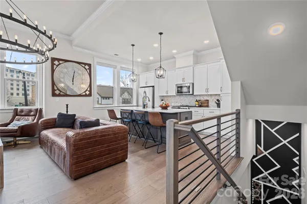 a living room with furniture kitchen view and a chandelier