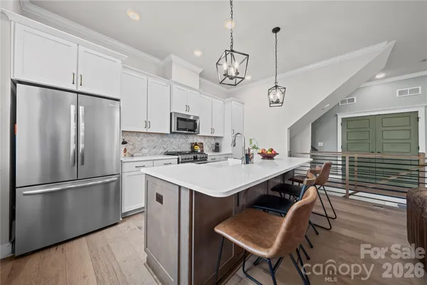 a kitchen with a refrigerator a stove a sink dishwasher a dining table and chairs with wooden floor