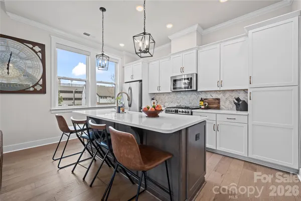 a kitchen with stainless steel appliances granite countertop a sink a stove a dining table and chairs