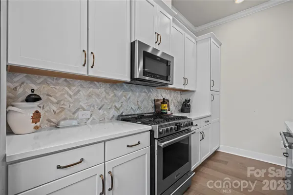a kitchen with stainless steel appliances granite countertop white cabinets and a stove top oven