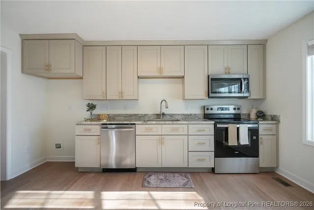 a kitchen with granite countertop white cabinets and stainless steel appliances