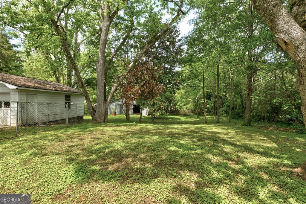 19 McDonough Street Hampton, GA 30228 - Photo 15 of 18 a backyard of a house with large trees and outdoor seating