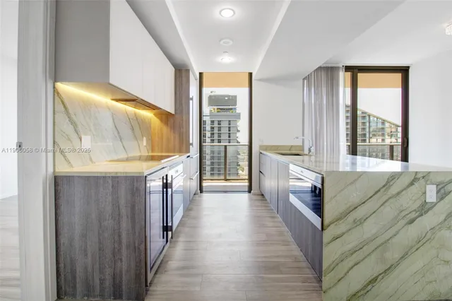 a view of a kitchen with kitchen island a sink a wooden floor and a large window