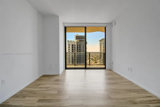 a view of an empty room with wooden floor and a window