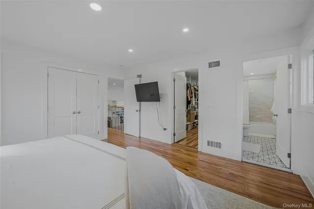a spacious bedroom with a bed and a wooden floor