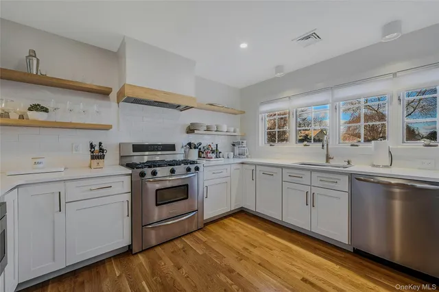 a kitchen with stainless steel appliances granite countertop a sink a stove a dining table and chairs with wooden floor