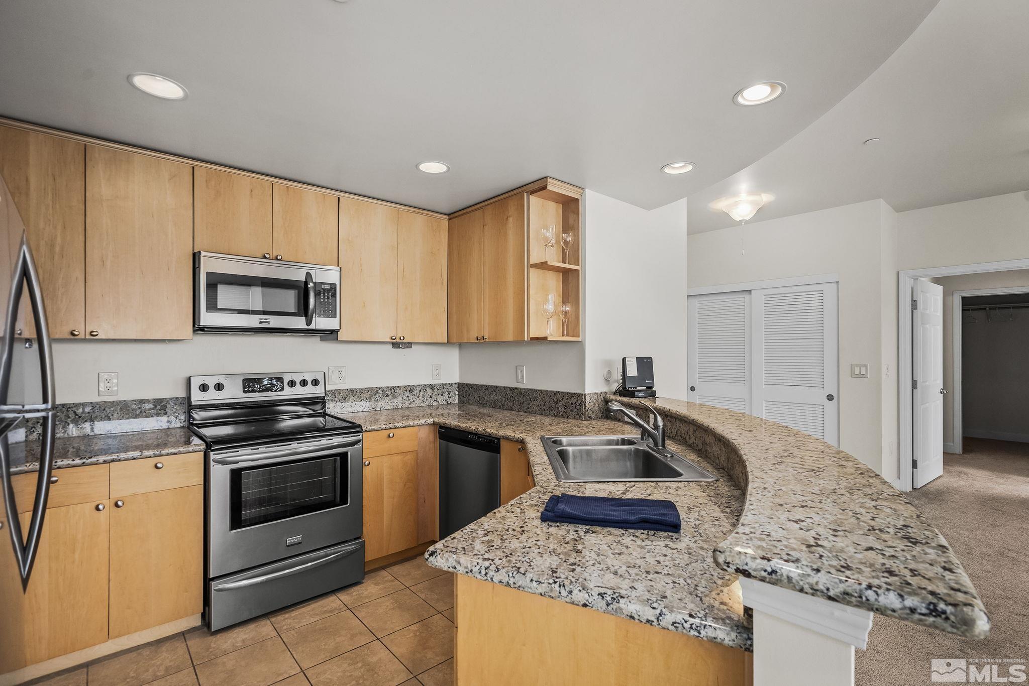 450 North Arlington Avenue, Unit 1207 Reno, NV 89503 - Photo 11 of 22 a kitchen with stainless steel appliances granite countertop a stove a sink and a microwave