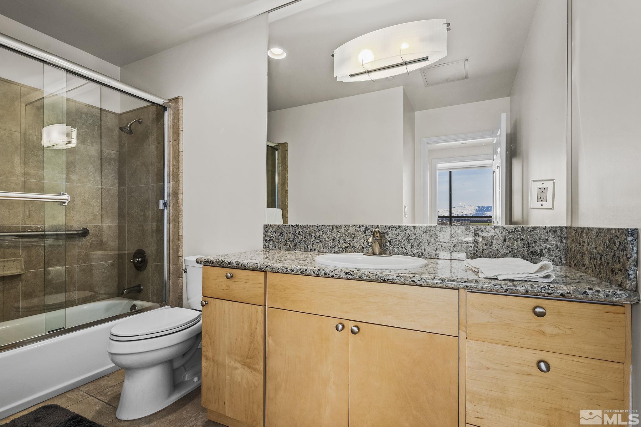 450 North Arlington Avenue, Unit 1207 Reno, NV 89503 - Photo 13 of 22 a bathroom with a granite countertop sink toilet a mirror and shower
