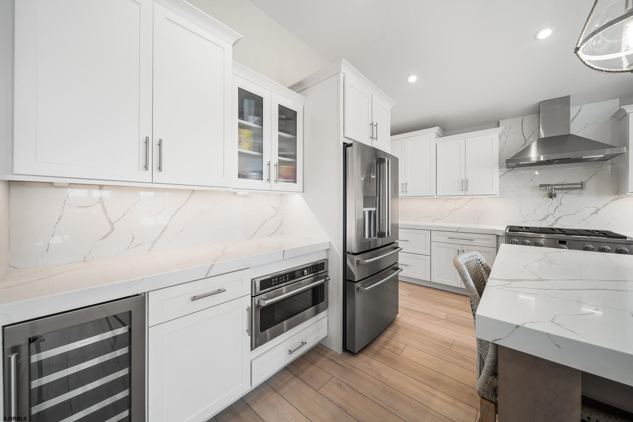 223 8th Street South Brigantine, NJ 08203 - Photo 28 of 46 a kitchen with a refrigerator stove and white cabinets with wooden floor
