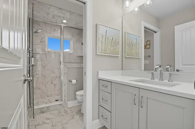 a bathroom with a granite countertop sink a toilet and shower