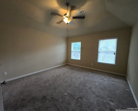 an empty room with a window and a ceiling fan