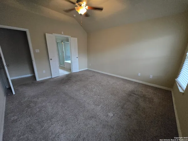 a view of an empty room with a chandelier fan