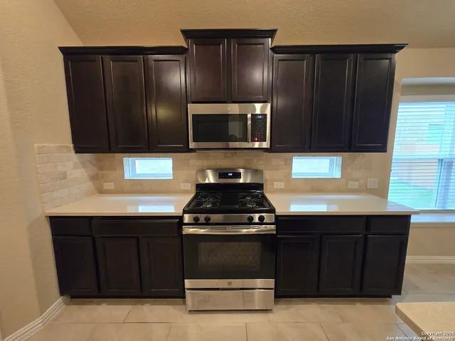 a kitchen with granite countertop wooden cabinets and stainless steel appliances