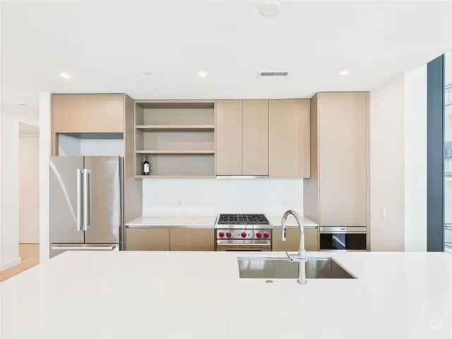 a kitchen with kitchen island a stove a refrigerator and white cabinets with wooden floor