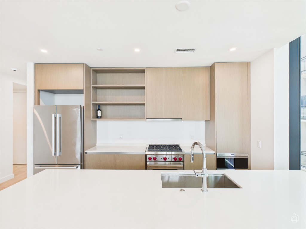 610 Davis Street, Unit 2808 Austin, TX 78701 - Photo 2 of 29 a kitchen with kitchen island a stove a refrigerator and white cabinets with wooden floor