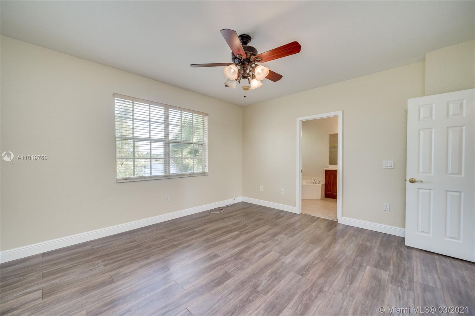 8437 Southwest 29th Street, Unit 102 Miramar, FL 33025 - Photo 23 of 29 an empty room with wooden floor chandelier fan and windows