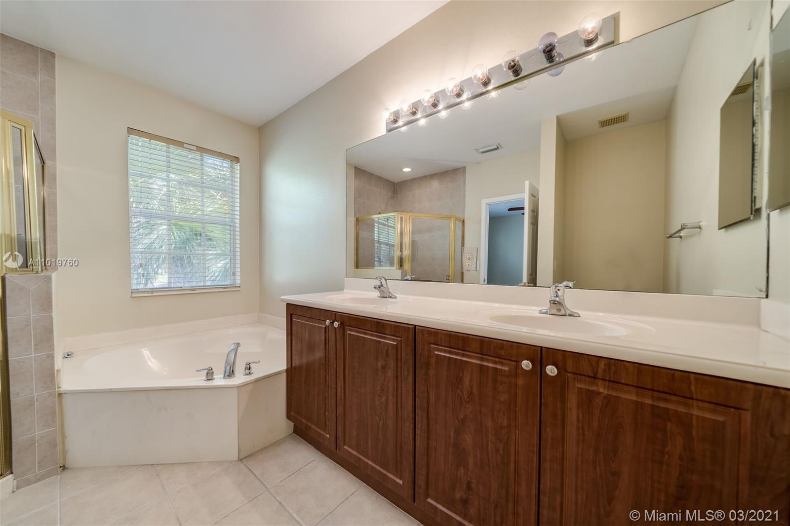 8437 Southwest 29th Street, Unit 102 Miramar, FL 33025 - Photo 24 of 29 a bathroom with a bathtub a double vanity sink and mirror