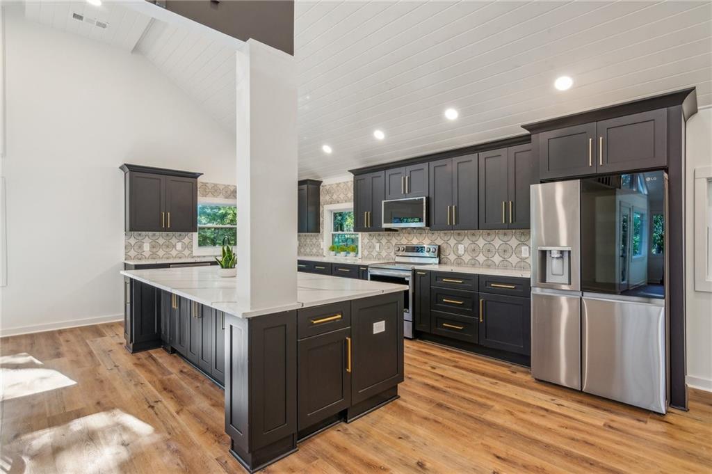 626 Petit Ridge Drive Big Canoe, GA 30143 - Photo 13 of 42 a kitchen with stainless steel appliances kitchen island granite countertop a stove a refrigerator a sink a oven with wooden cabinets and wooden floor