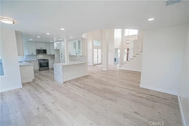 a open kitchen with white cabinets and wooden floor
