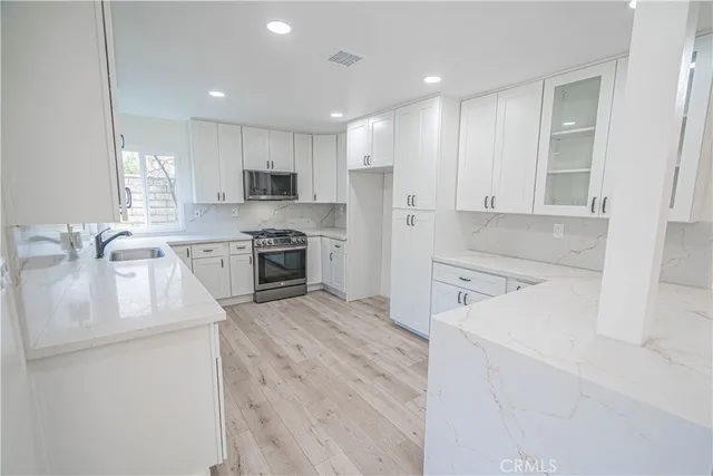 a kitchen with a sink white cabinets and stainless steel appliances