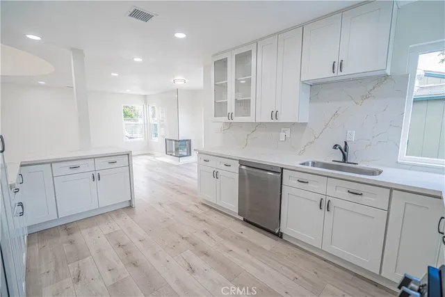 a kitchen with white cabinets stainless steel appliances sink and wooden floor