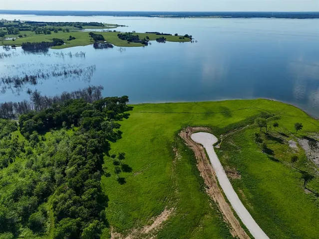 a view of a lake with a yard and large trees