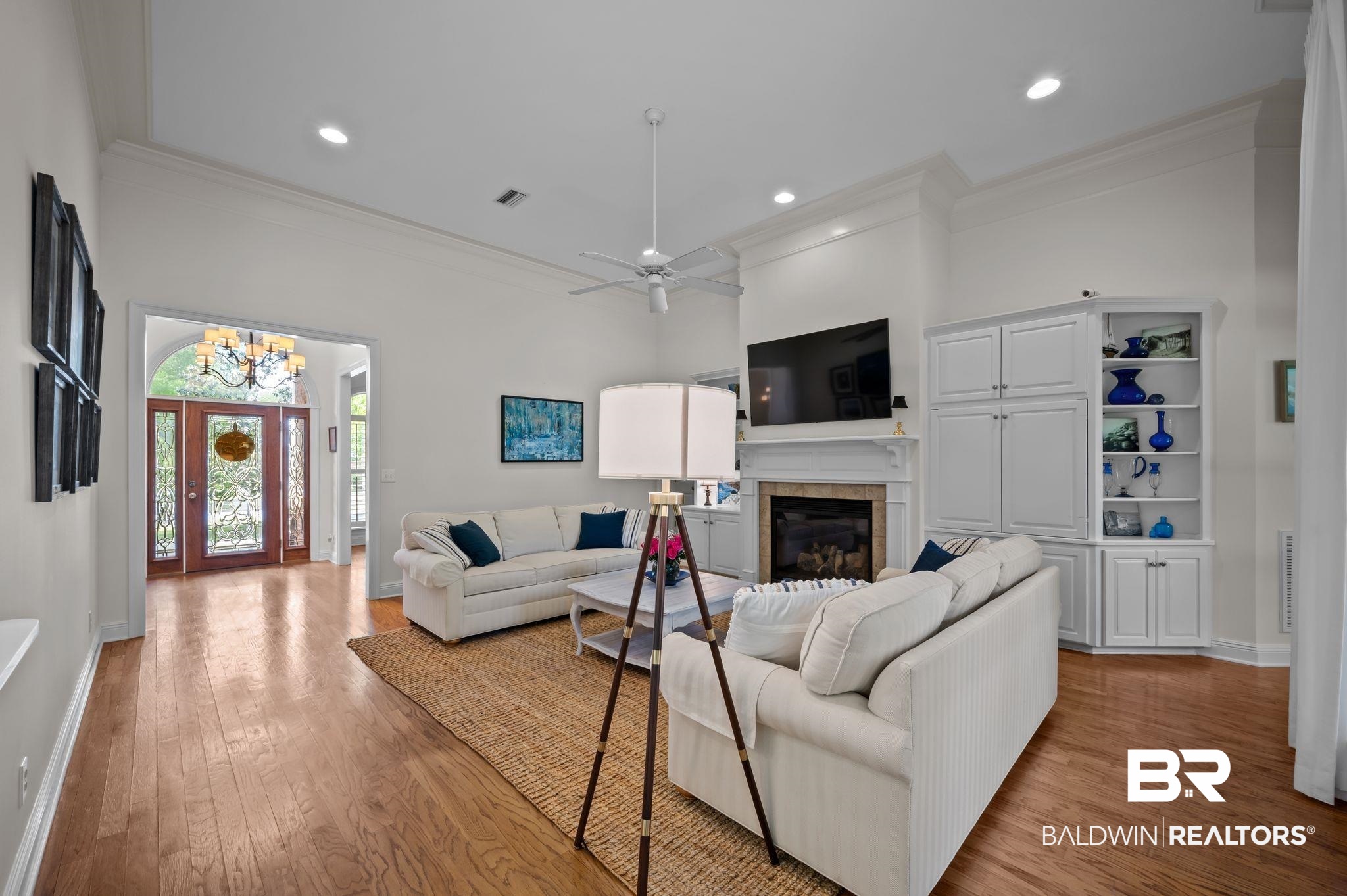 30151 Dolive Ridge Daphne, AL 36527 - Photo 6 of 37 Living room featuring crown molding, visible vents, baseboards, wood finished floors, and ceiling fan with notable chandelier
