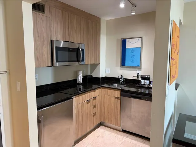 a kitchen with granite countertop white cabinets stainless steel appliances and a sink