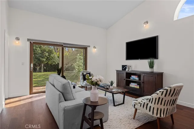 a living room with furniture floor to ceiling window hardwood floor and a flat screen tv