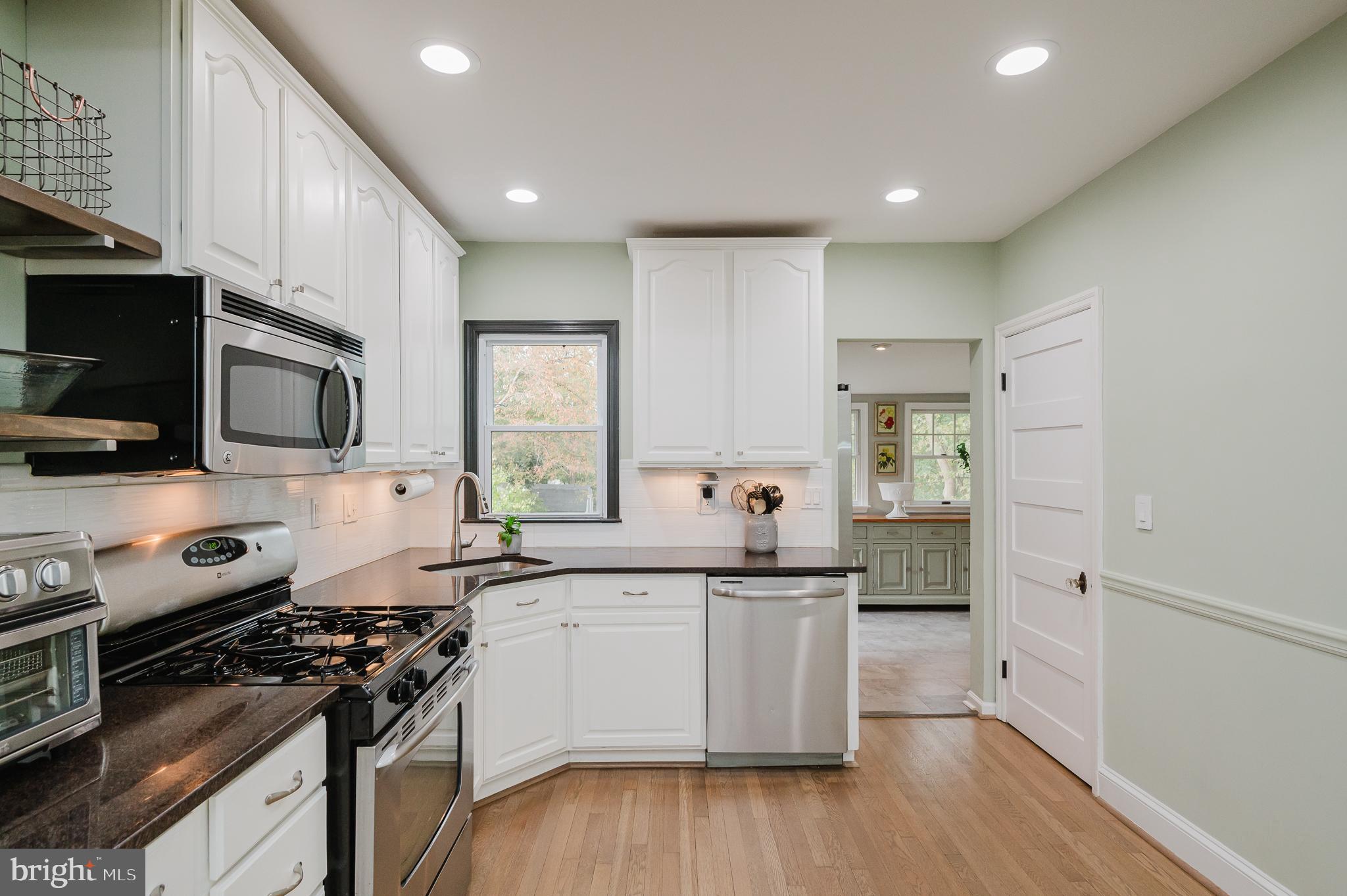 616 Sudbrook Road Baltimore, MD 21208 - Photo 19 of 58 a kitchen with stainless steel appliances a sink dishwasher a stove and a microwave oven with wooden floor