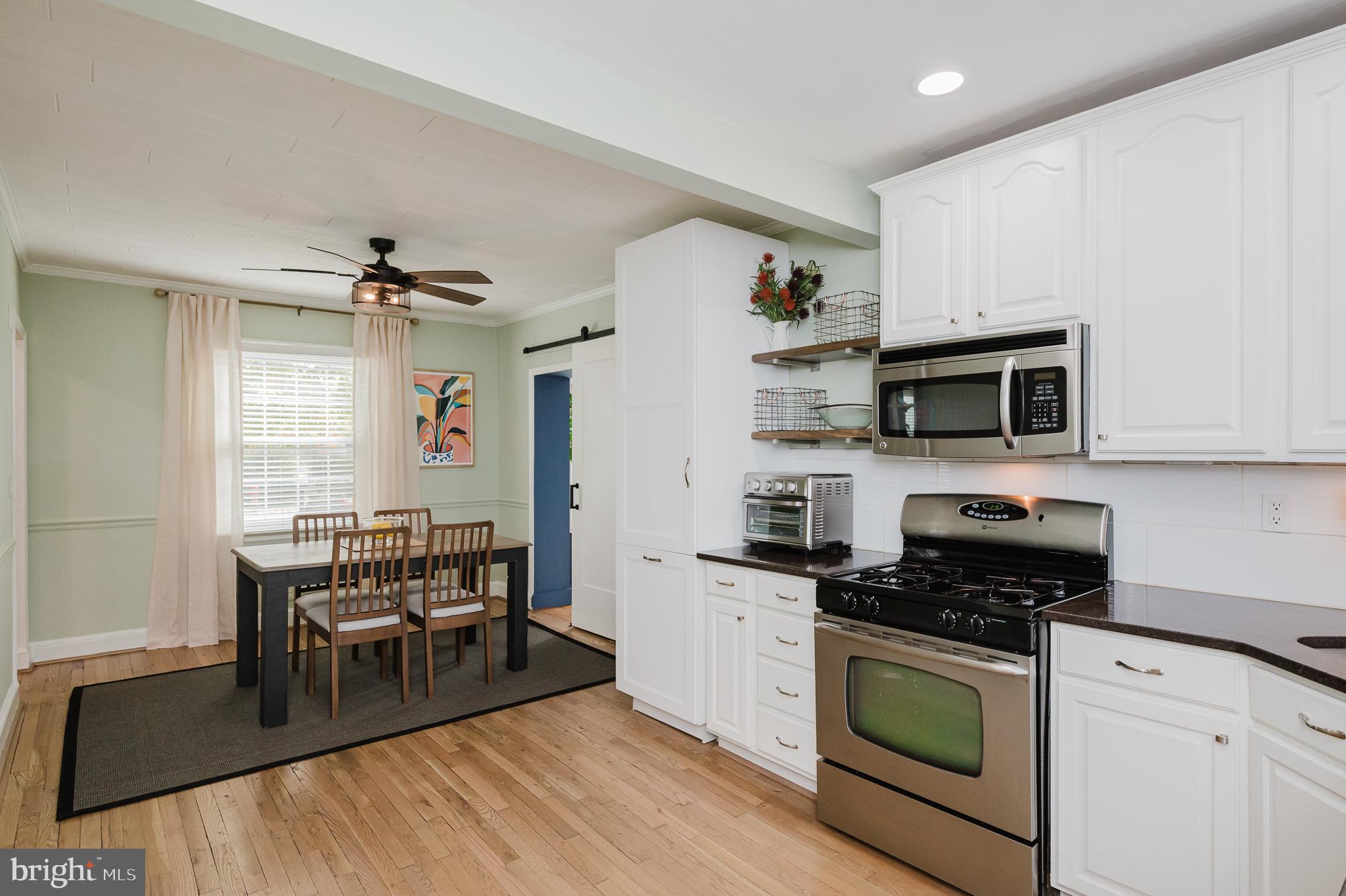 616 Sudbrook Road Baltimore, MD 21208 - Photo 20 of 58 a kitchen with stainless steel appliances kitchen island granite countertop a stove top oven a sink a dining table and chairs with wooden floor