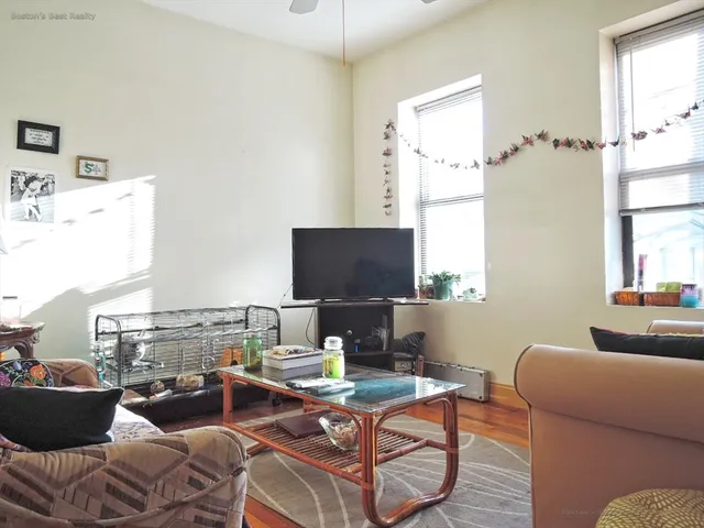 a view of a hallway with wooden floor and a living room