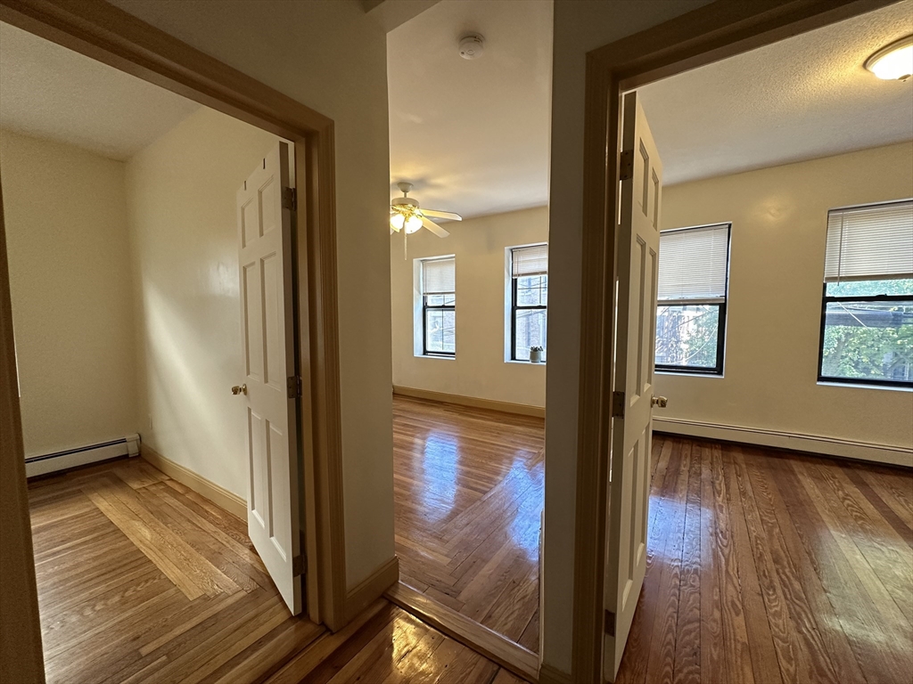 181 Allston, Unit 2 Boston, MA 02134 - Photo 17 of 18 a view of a hallway with wooden floor and a living room