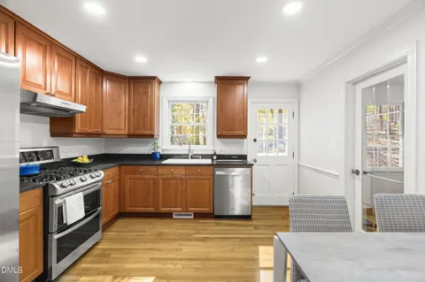 a kitchen with stainless steel appliances granite countertop a refrigerator a stove and a sink with wooden floor