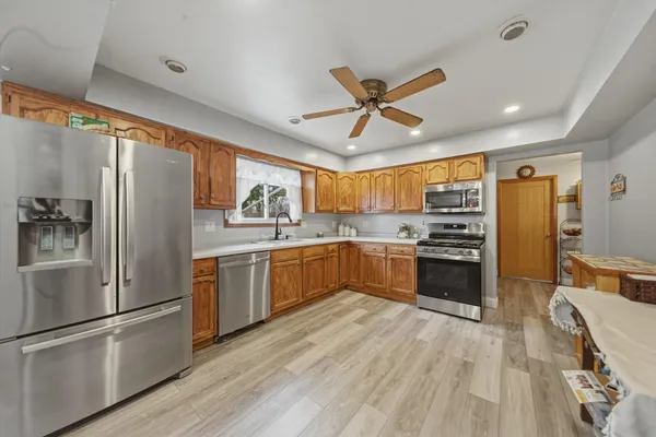 a kitchen with stainless steel appliances a refrigerator a sink dishwasher a stove and white countertops with wooden floor