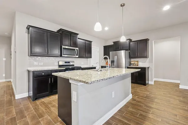 a kitchen with stainless steel appliances granite countertop a refrigerator a stove a sink and a microwave