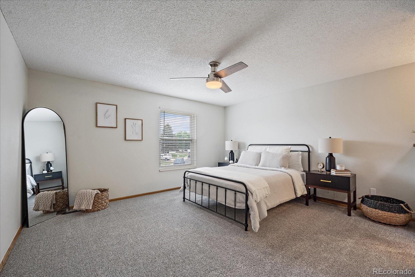 10961 Gray Circle Westminster, CO 80020 - Photo 12 of 24 a spacious bedroom with a bed a couch and a chandelier