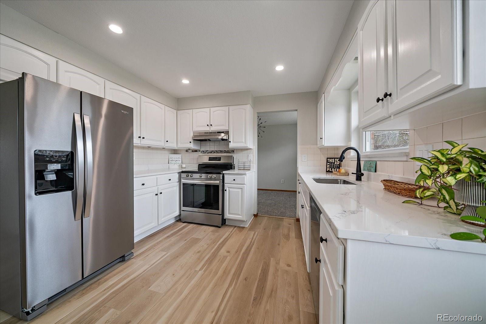 10961 Gray Circle Westminster, CO 80020 - Photo 6 of 24 a kitchen with stainless steel appliances a refrigerator sink and wooden floor