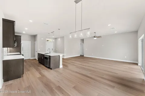 a large kitchen with kitchen island a stove a sink dishwasher a refrigerator and white cabinets with wooden floor